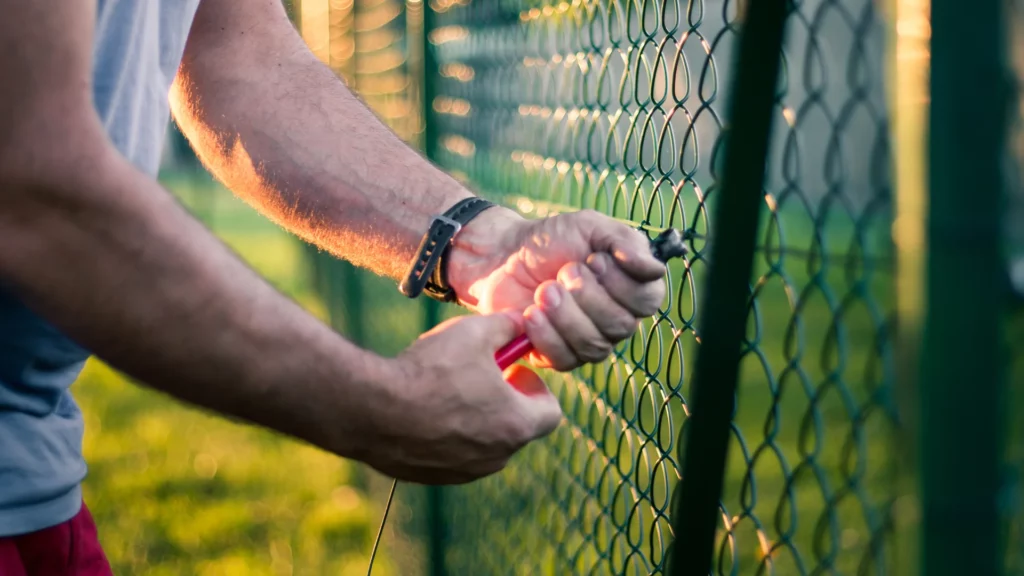 Montaż siatki ogrodzeniowej na metalowym słupku przy użyciu akcesoriów montażowych Arwex.